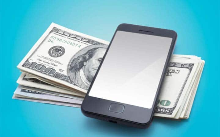 smart phone sitting on a pile of money