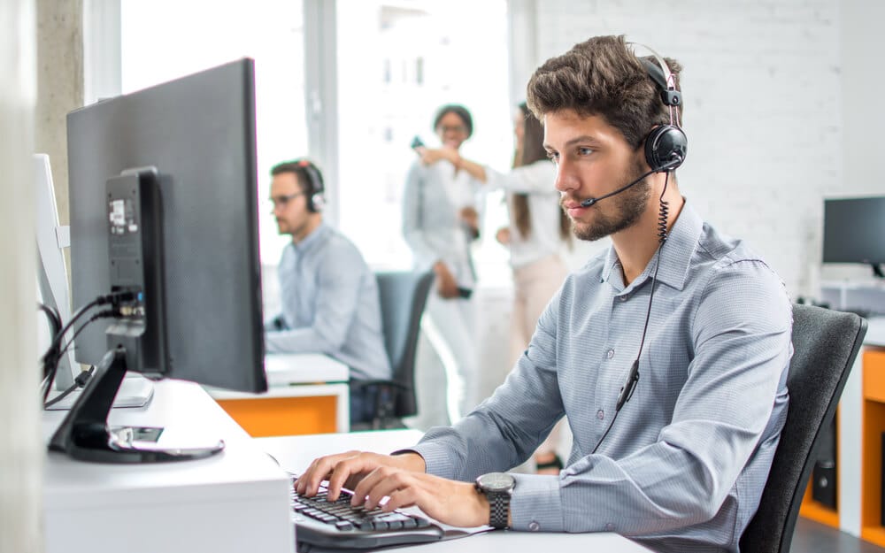 IT support worker sitting at computer wearing headset